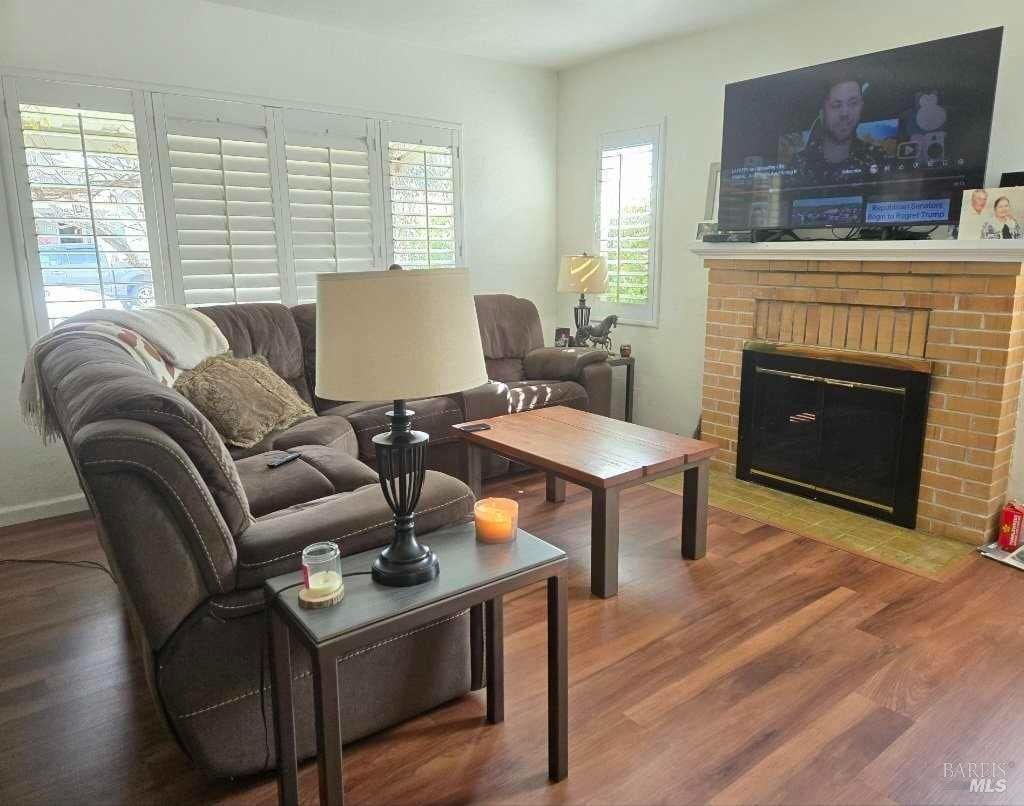 living area featuring a fireplace, wood finished floors, and baseboards