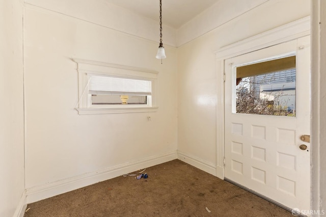 interior space with baseboards, dark carpet, and a healthy amount of sunlight