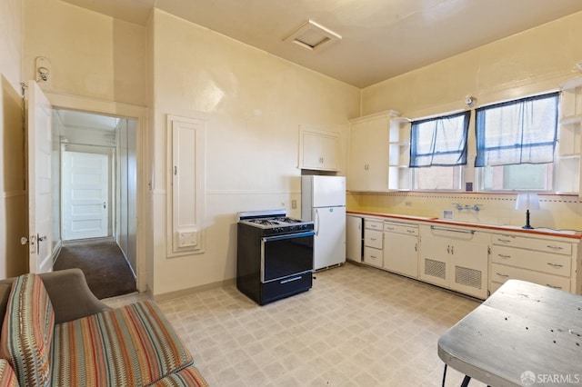 kitchen featuring light floors, gas stove, backsplash, and freestanding refrigerator