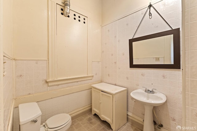 bathroom with toilet, tile patterned flooring, and tile walls