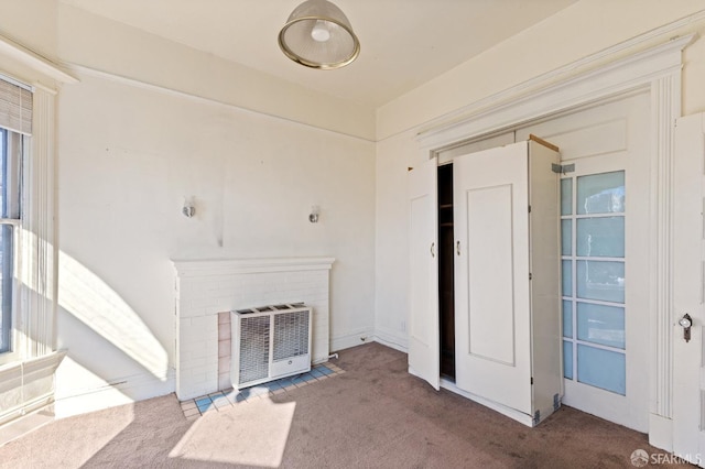 unfurnished living room with carpet, a fireplace, and heating unit