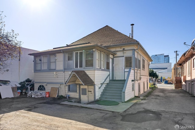 view of front of house with a shingled roof and a sunroom