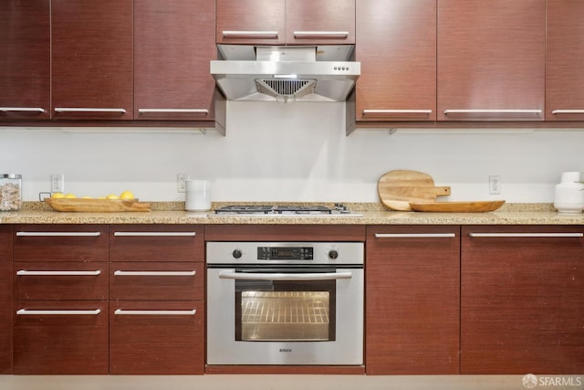 kitchen with light stone counters, appliances with stainless steel finishes, and exhaust hood