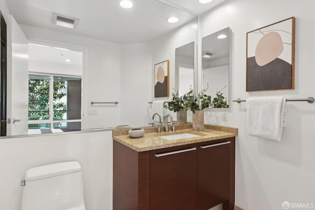 bathroom featuring vanity, toilet, recessed lighting, and visible vents