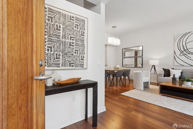 entrance foyer featuring baseboards, an inviting chandelier, and wood finished floors