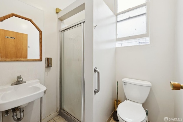 bathroom featuring a stall shower, toilet, and a sink