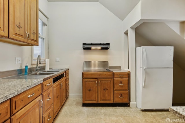 kitchen featuring freestanding refrigerator, exhaust hood, a sink, brown cabinets, and lofted ceiling