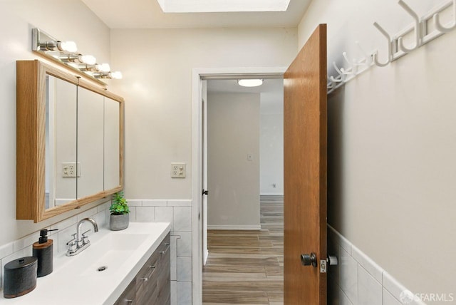278 7th Ave, San Francisco, CA 94118 - bathroom featuring a skylight, tile walls, vanity, wainscoting, and wood finished floors
