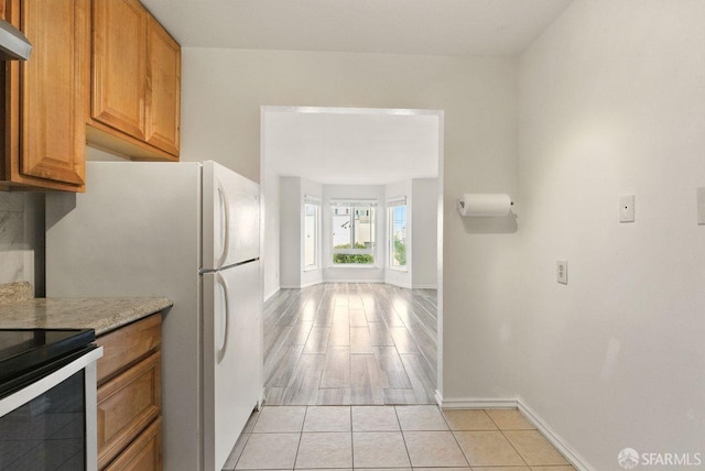 278 7th Ave, San Francisco, CA 94118 - kitchen with brown cabinets, stainless steel electric range oven, light tile patterned flooring, and freestanding refrigerator