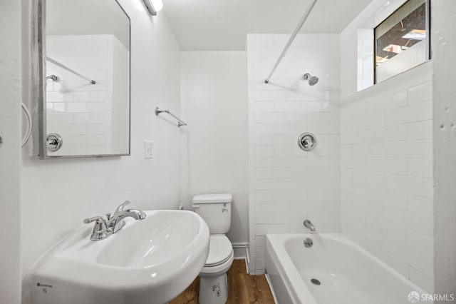 full bathroom with hardwood / wood-style flooring, toilet, tiled shower / bath, and sink