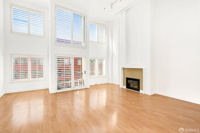 unfurnished living room featuring a high ceiling, light wood-type flooring, and track lighting