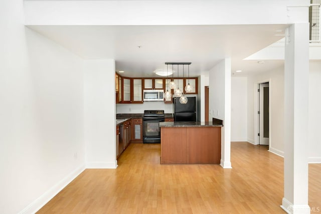 kitchen featuring kitchen peninsula, pendant lighting, light hardwood / wood-style flooring, and black appliances