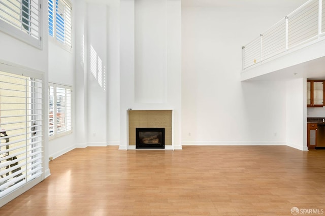 unfurnished living room featuring a high ceiling and light hardwood / wood-style flooring