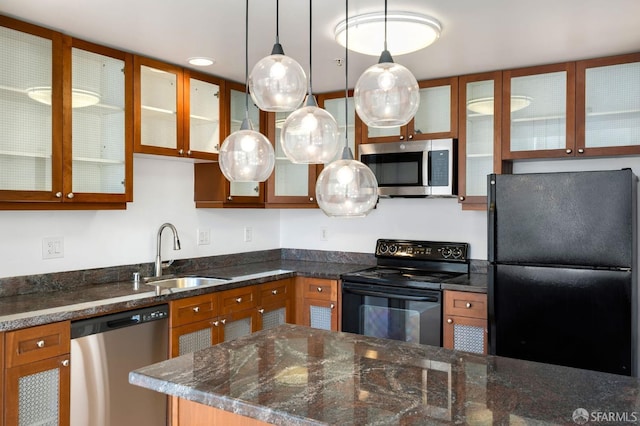 kitchen featuring appliances with stainless steel finishes, decorative light fixtures, dark stone counters, and sink