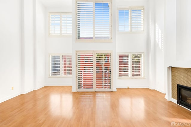 unfurnished living room featuring a fireplace, hardwood / wood-style floors, and a towering ceiling