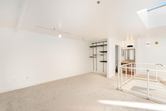 empty room with a skylight, light carpet, and track lighting