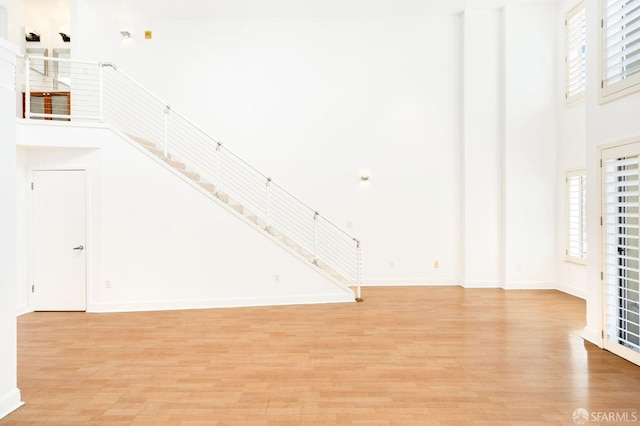 unfurnished living room with a high ceiling and light hardwood / wood-style floors