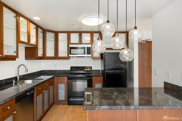 kitchen with sink, hanging light fixtures, dark stone countertops, and black appliances