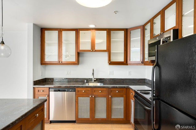 kitchen with dark stone countertops, hanging light fixtures, black appliances, and sink