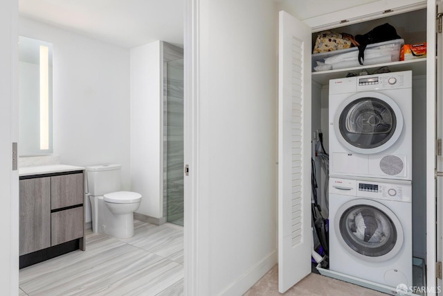washroom featuring baseboards, stacked washer and dryer, and laundry area