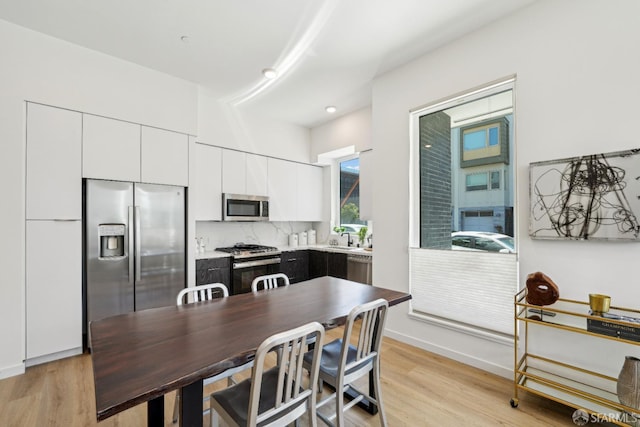 kitchen with light countertops, white cabinetry, light wood-type flooring, stainless steel appliances, and decorative backsplash