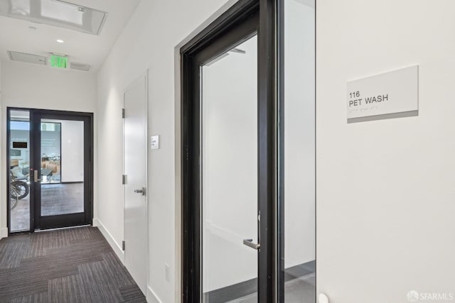 hallway featuring baseboards and dark colored carpet