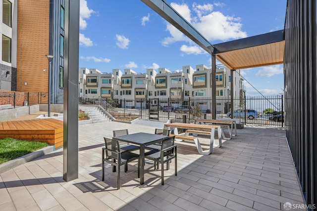view of patio / terrace with fence, outdoor dining area, and a residential view