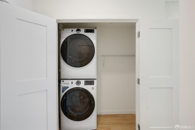 laundry room with light wood-style flooring, stacked washer / dryer, and laundry area
