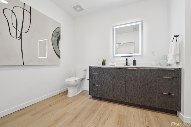 bathroom featuring vanity, toilet, baseboards, visible vents, and wood finished floors