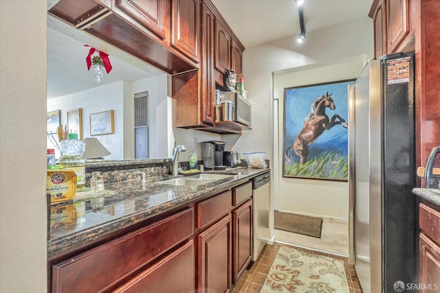 kitchen featuring sink, rail lighting, stainless steel appliances, dark stone counters, and light tile patterned floors