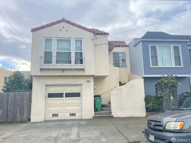 view of front of property featuring stucco siding, fence, a tiled roof, driveway, and a garage
