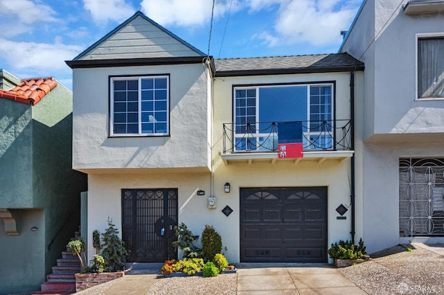 view of property featuring stucco siding, driveway, a balcony, and an attached garage