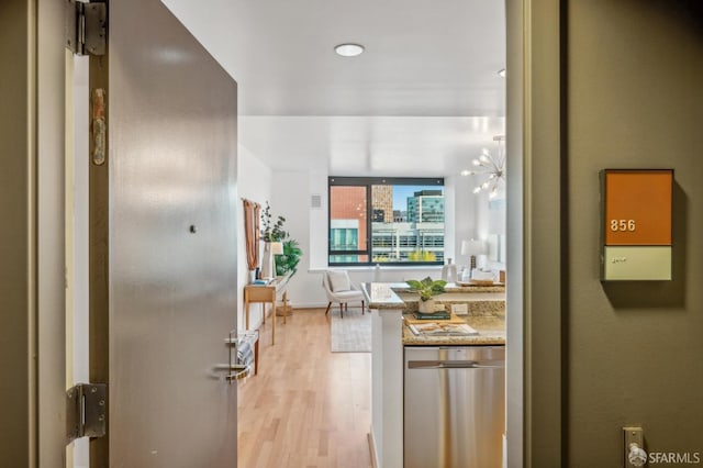 kitchen with dishwasher, light wood-type flooring, a chandelier, and light stone counters