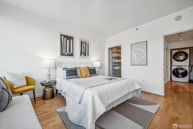 bedroom with hardwood / wood-style flooring and stacked washer and clothes dryer