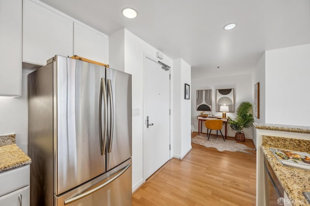 kitchen featuring white cabinetry, light hardwood / wood-style flooring, light stone counters, and stainless steel fridge