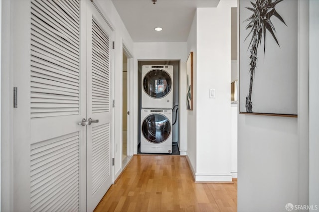 laundry area with stacked washer and dryer and light hardwood / wood-style floors