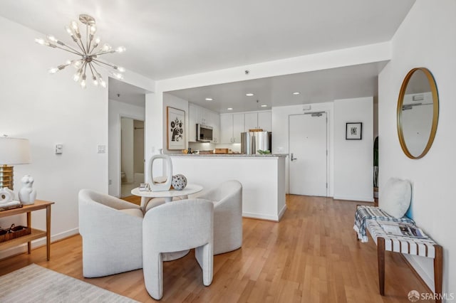 dining room with light hardwood / wood-style floors and a notable chandelier