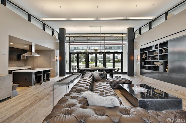 living room featuring a towering ceiling, french doors, and light hardwood / wood-style flooring