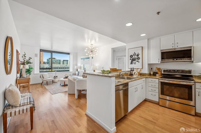 kitchen with light hardwood / wood-style flooring, white cabinetry, kitchen peninsula, and stainless steel appliances