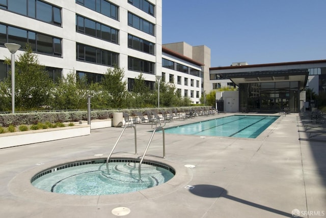 view of swimming pool with a hot tub and a patio