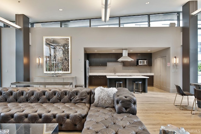 living room with light hardwood / wood-style flooring, sink, and vaulted ceiling