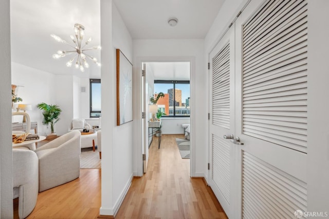 hall featuring light hardwood / wood-style flooring and an inviting chandelier