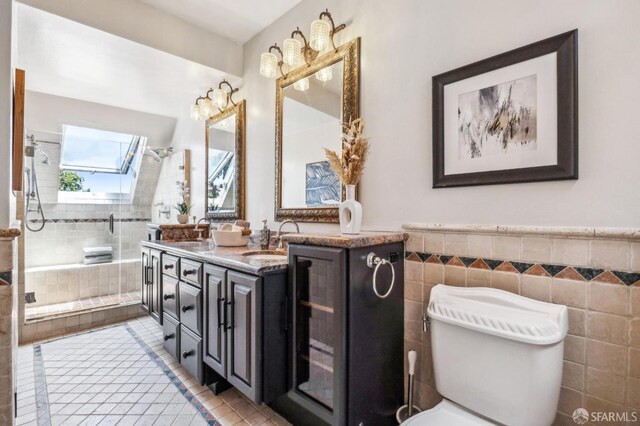 68 Castro St, San Francisco, CA 94114 - bathroom featuring a skylight, double vanity, tile patterned flooring, a shower stall, and tile walls