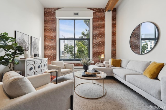 living area featuring brick wall, visible vents, and beam ceiling