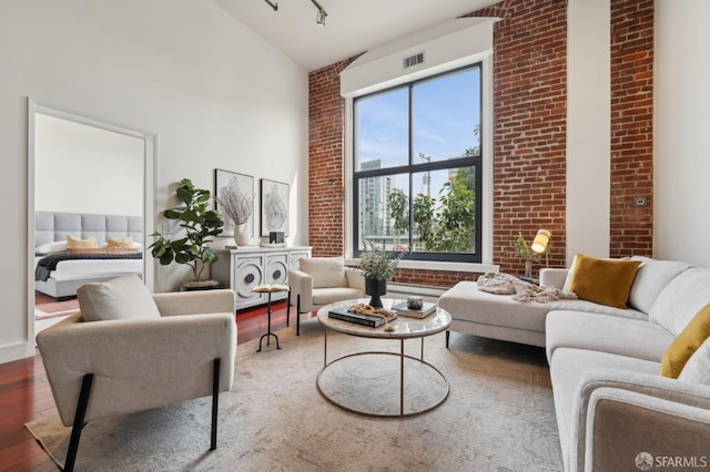 310 Townsend St Unit 202, San Francisco, CA 94107 - living room featuring high vaulted ceiling, visible vents, brick wall, and wood finished floors