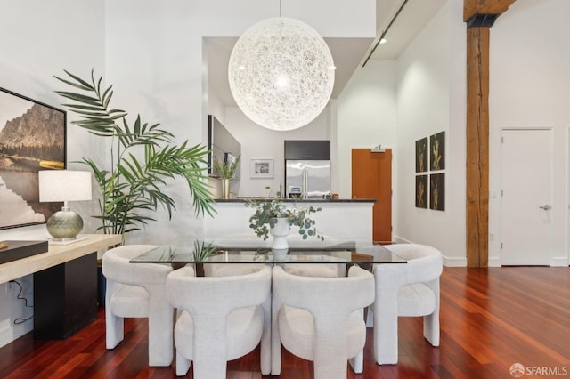 dining space with a high ceiling, wood finished floors, and an inviting chandelier