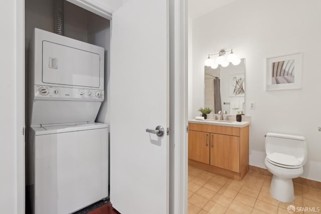 washroom with a sink, stacked washing maching and dryer, and light tile patterned floors