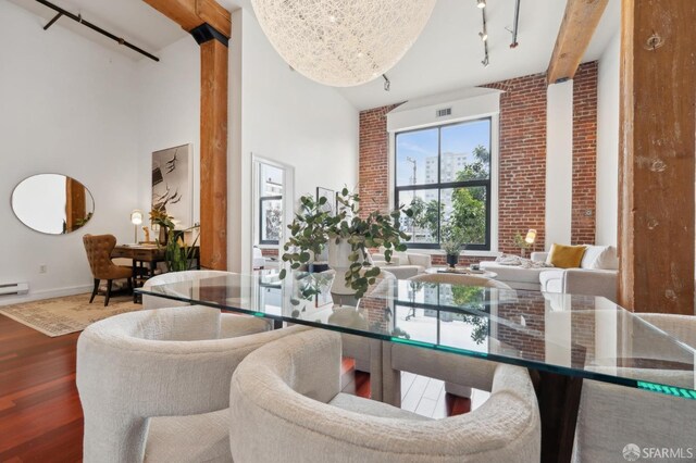 dining room with brick wall, a high ceiling, wood finished floors, and rail lighting