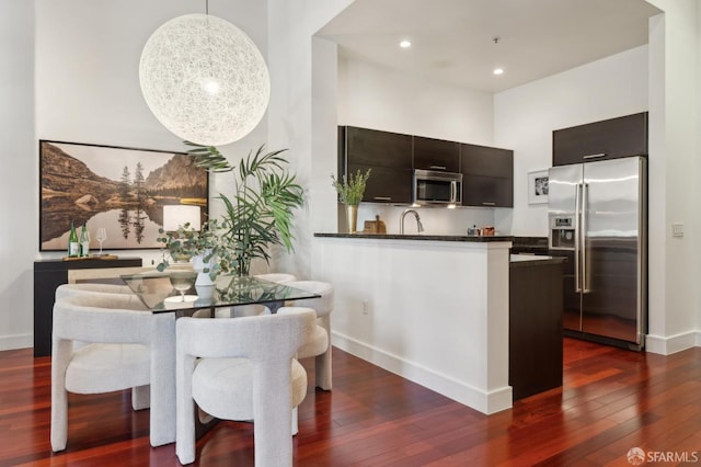 kitchen featuring appliances with stainless steel finishes, dark countertops, dark wood finished floors, and baseboards