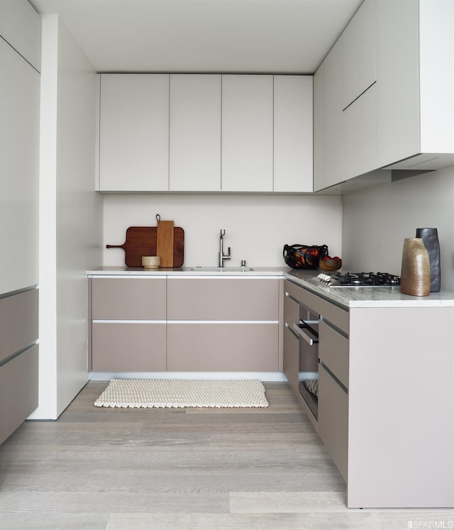 181 Fremont St Unit 65C, San Francisco, CA 94105 - kitchen with light countertops, light wood-style flooring, modern cabinets, and white cabinetry